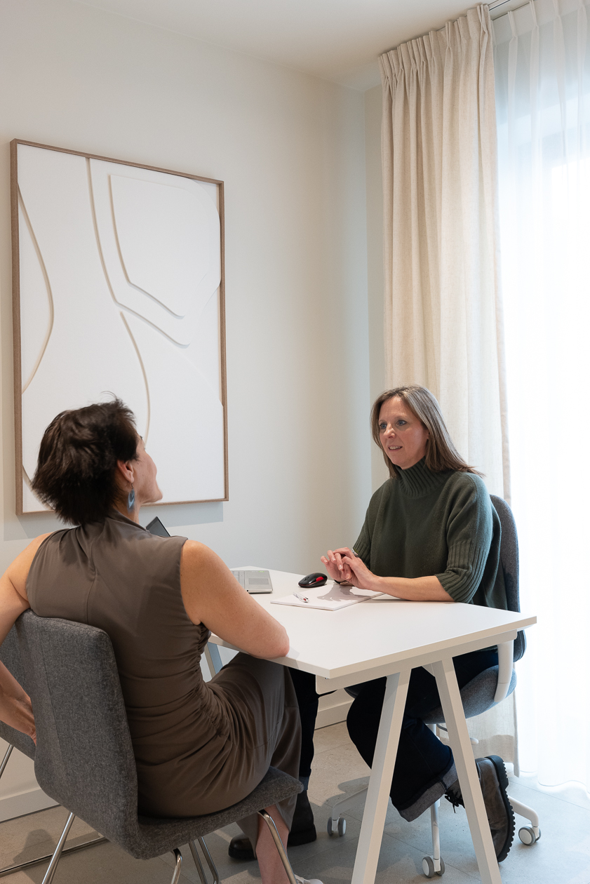 gesprek tussen twee vrouwen aan een tafel. de enen vrouw is een therapeut en de andere is de patiënt.